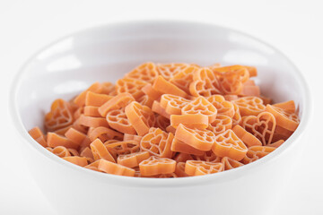 Bowl of raw heart shaped pasta on white background