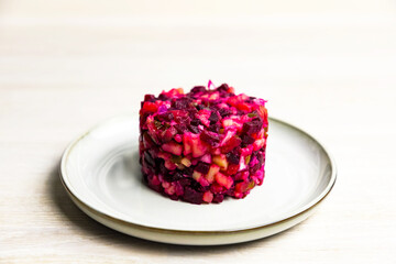 Beetroot Russian salad of boiled vegetables in grey white plate on white table background. Close up.