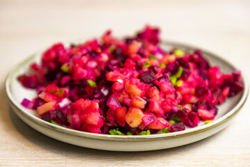 Russian Vinegret beet salad of boiled vegetables in grey white plate on white table background.
