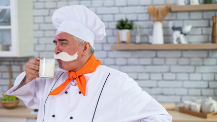A friendly elderly milkman with a glass of milk. Portrait of a male farmer with a bushy mustache.