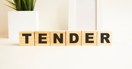 Wooden cubes with letters on a white table. The word is TENDER. White background.