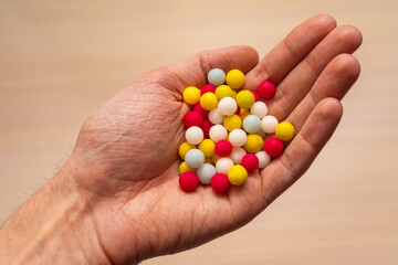 multicolored sugar tablets in the palm. Candy in the form of balls of different colors in hand