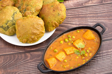 Delicious Indian Palak Poori Or Paalak Puri Made Of Wheat Flour Gehoon Ka Aata Mixed With Blenched Spinach Leaves Served With Alu Matar Sabzi Or Veg Curry Sabji. Wooden Background With Copy Space