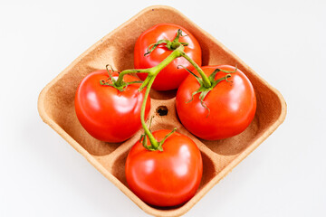 Fresh tomatoes on biodegradable pulp paper food tray isolated on white. Recyclable packaging concept.  Top view, copy space