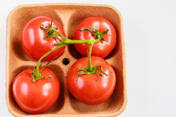 Close up of fresh tomatoes on biodegradable pulp paper food tray isolated on white. Recyclable packaging, sustainable consumption concept. Top view, stock photo