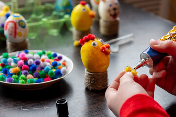 Children's hands apply glue to the egg craft element