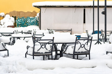 Empty tables and chairs covered by the snow. Covid or Coronavirus affects the global food industry, restaurants and bar daily traffic dropped