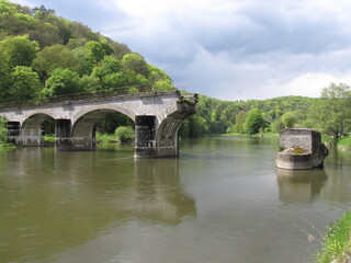 Fototapeta premium the famous bombed bridge over river semois between green hills with a forest with pine trees in springtime in bohan in the belgian ardennes