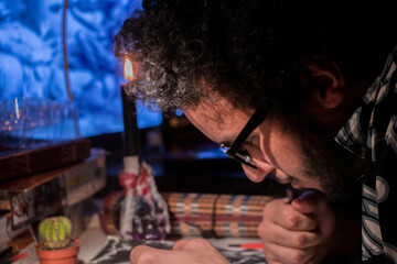 an artist and content creator recording a video for his channel in studio at home, focused on drawing under candle light
