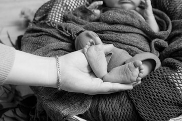 Cute little baby feet in mom's arms. Happy motherhood 