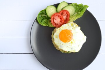 Nasi goreng or Indonesian fried rice with egg garnished with  lettuce, fresh cucumber slices , slice tomato and sunny side up. Flat lay
