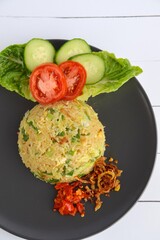 Nasi goreng or Indonesian fried rice with egg garnished with  lettuce, fresh cucumber slices , slice tomato and sambal 