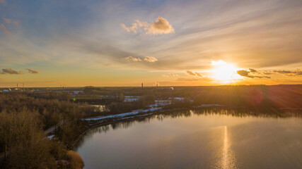 Aerial view of a beautiful and dramatic sunset over a forest lake reflected in the water, landscape drone shot. Blakheide, Beerse, Belgium. High quality photo