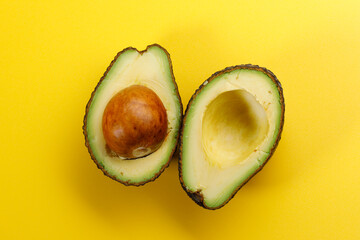 Avocado cut in half on a Yellow background