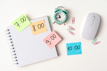 Color notes with time on desktop with notepad, alarm clock. Copy space. The concept of planning the day, schedule.