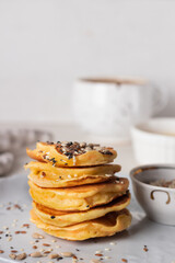 Fototapeta na wymiar Stack of golden pancakes with various seeds and coffee. 
