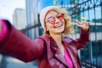 Woman  with  curly  hairs  in   leather jacket  making self portrait on the street. Urban...
