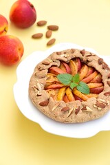 Galette with peaches and almond nuts garnish with mint verbena leaf. Selective focus