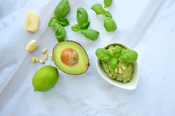Basil avocado pesto sauce with main ingredients: fresh basil leaves, avocado, parmesan cheese, pine...