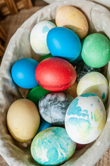Basket with colored Easter eggs on brown wooden surface