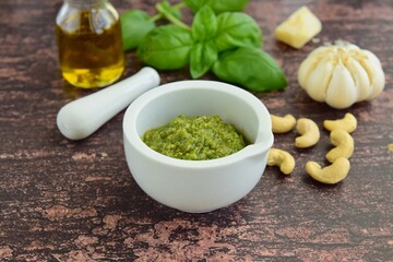 Basil avocado pesto sauce with main ingredients: fresh basil leaves, avocado, parmesan cheese, pine nuts, garlic and lime