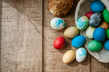 Basket with colored Easter eggs and Easter cake lie on a brown wooden surface