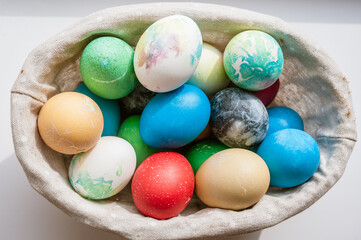 Fototapeta na wymiar Basket with colored Easter eggs on a white surface