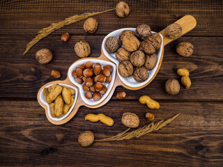 Fototapeta na wymiar Walnut, hazelnuts and peanuts on a wooden background, in a white plate in the shape of a heart. Food.