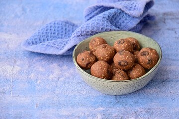 Homemade healthy energy balls with chocolate, raisin, quinoa and oat on blue background
