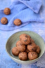Homemade healthy energy balls with chocolate, raisin, quinoa and oat on blue background
