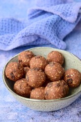 Homemade healthy energy balls with chocolate, raisin, quinoa and oat on blue background
