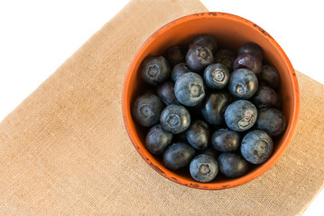 Fresh juicy tasty blueberries in a small clay bowl. 