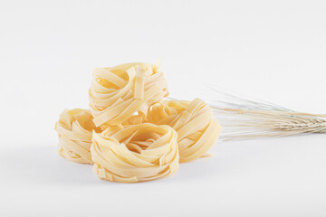Raw uncooked homemade italian pasta tagliatelle on a light background