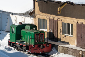 old retro shunting diesel locomotive at the repair station. Snow-covered railway station and...