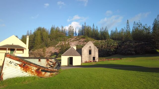 right to left panning motion of old Norfolk Island Lighter boat at sunrise with the ruins of the old Crankmill and Pier Store Museum in background, Norfolk Island,Australia