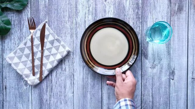 top view of person hand putting empty plate on table 