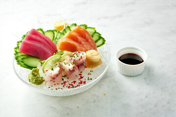 Classic Japanese sashimi set of raw salmon, eel and tuna with lime, cucumber on plate on a marble background. Close up, selective focus