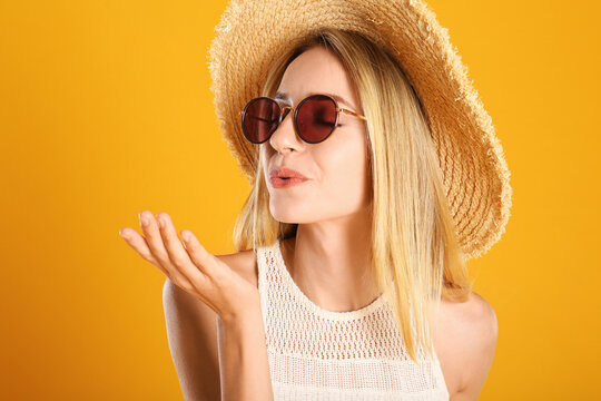 Beautiful woman in stylish sunglasses on yellow background