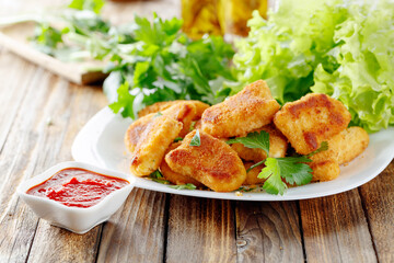 Nuggets and salad on a old wooden table.