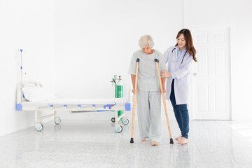asian old patient learning to use crutches with female doctor, walk training and rehabilitation,...