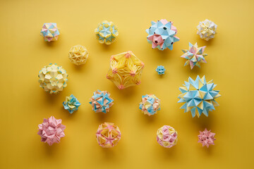 Set of multicolor handmade modular origami balls or Kusudama Isolated on yellow background. Visual...