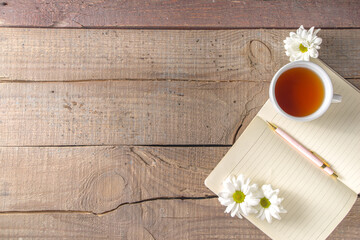 Chamomile flowers, notebook and tea background
