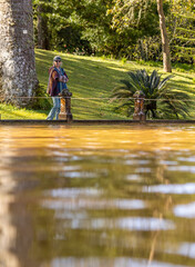 Woman walking in Terra Nostra park, thermal water pool, Azores.