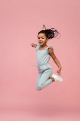 Jumping. Happy longhair brunette little girl isolated on pink studio background with copyspace for ad. Looks happy, cheerful, sincere. Childhood, education, human emotions, facial expression concept.