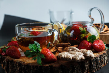 Glass teapot. Still life with hot tea with lemon and strawberries. Wooden stand. Splash.