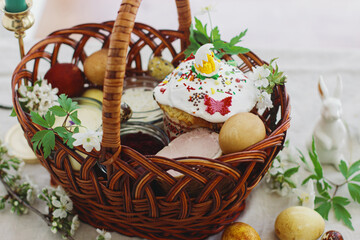 Stylish easter eggs, homemade Easter bread, traditional Easter food in  basket on rustic table