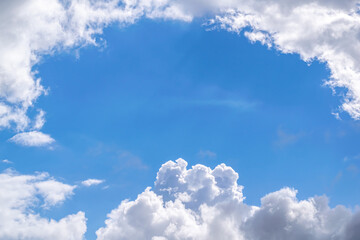Naklejka na ściany i meble A patch of blue sky surrounded by clouds on a clear sunny day.
