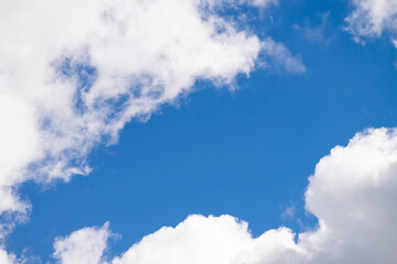 A patch of clear sky among fluffy white clouds.