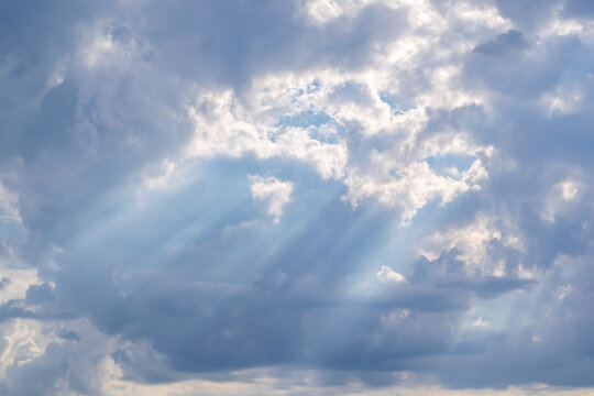 The sky is covered with clouds through which the rays of the sun break through.