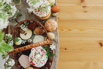 Easter food, eggs, beets, cheese, butter, ham, Easter bread in  basket with flowers on rustic table